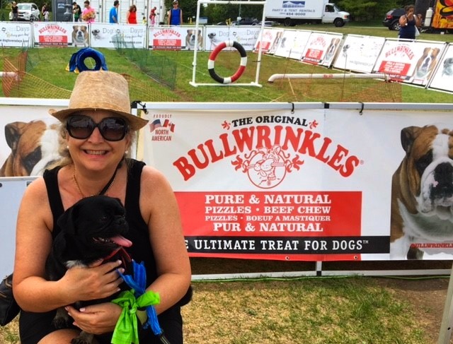 Susie and Kilo the Pug having fun in the sun at Paws in the Park in front of Bullwrinkles sign