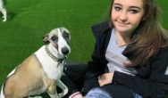 girl poses with her dog on grass