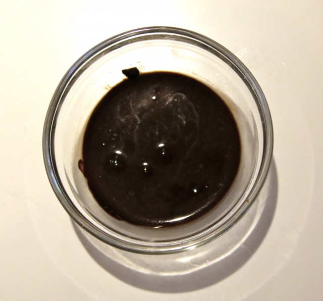 chocolate substitute Carob in liquid form in small glass bowl on white counter top
